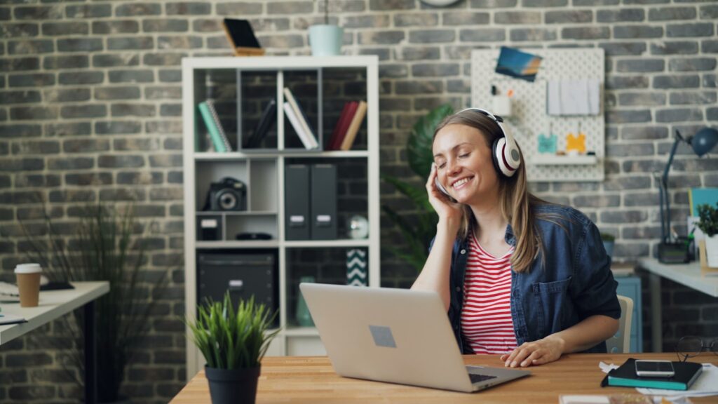 a woman sitting in front of a laptop computer wearing headphones